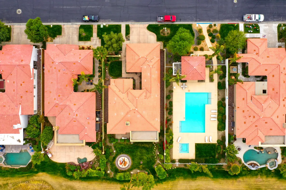 Aerial view of tile-roof homes with backyard pools and desert landscaping