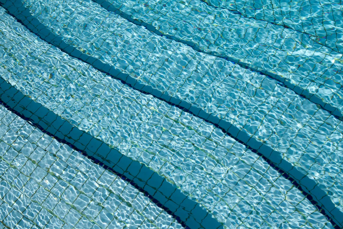 Tiled pool steps under clear, rippling blue water